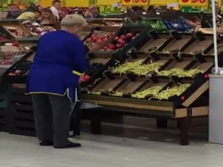 Supermarket Employee Putting Floor Veggies Back